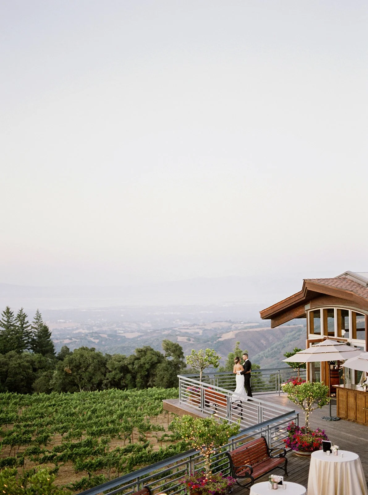 Bride and groom embrace on the vineyard terrace overlooking the Santa Cruz Mountains at Thomas Fogarty Winery.