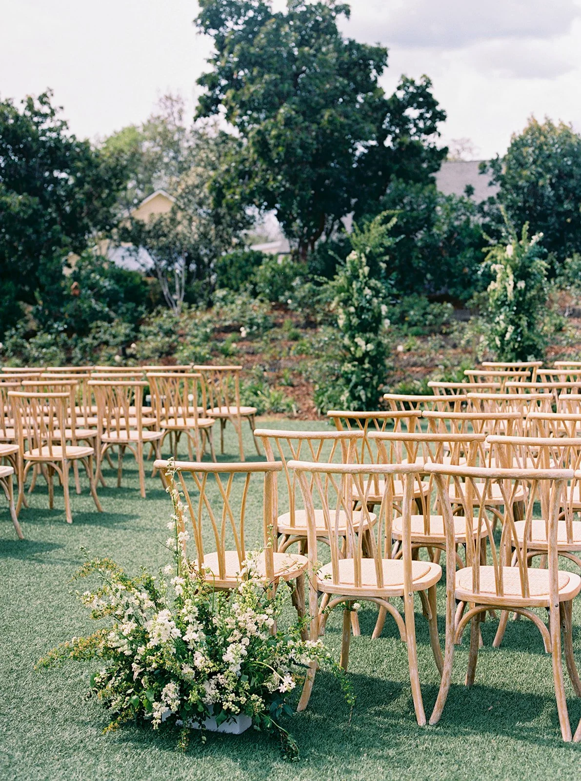 Close-up of aisle floral arrangements and wooden ceremony seating for a wedding at Solage Napa Valley.