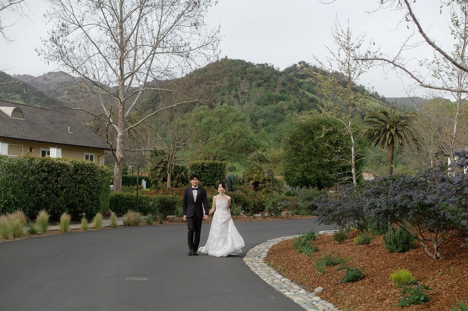 Bride and groom walking outdoors at Solage Calistoga with lush greenery and mountain backdrop.