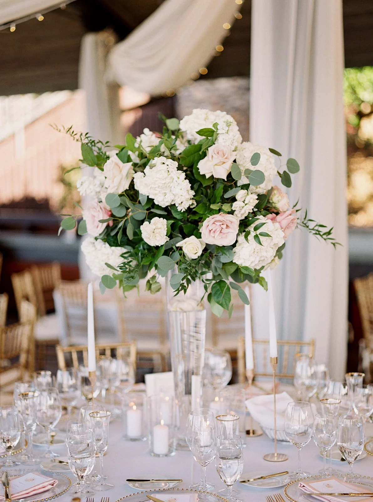 Elegant wedding reception table with tall floral centerpiece and candlelight at Thomas Fogarty Winery.
