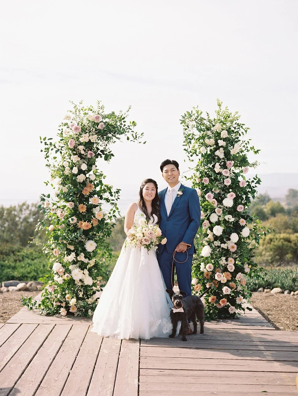 Couple standing beneath floral ceremony arches at Dos Pueblos Orchid Farm wedding in Santa Barbara.
