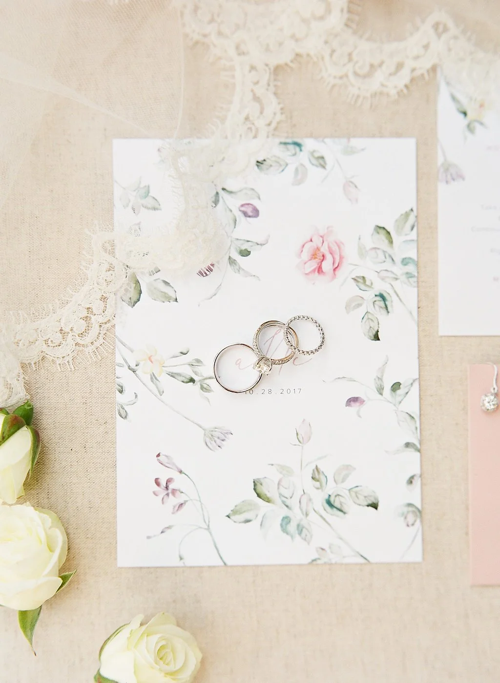 Wedding invitation flatlay with rings and soft floral details for a Mountain Winery wedding in Saratoga.