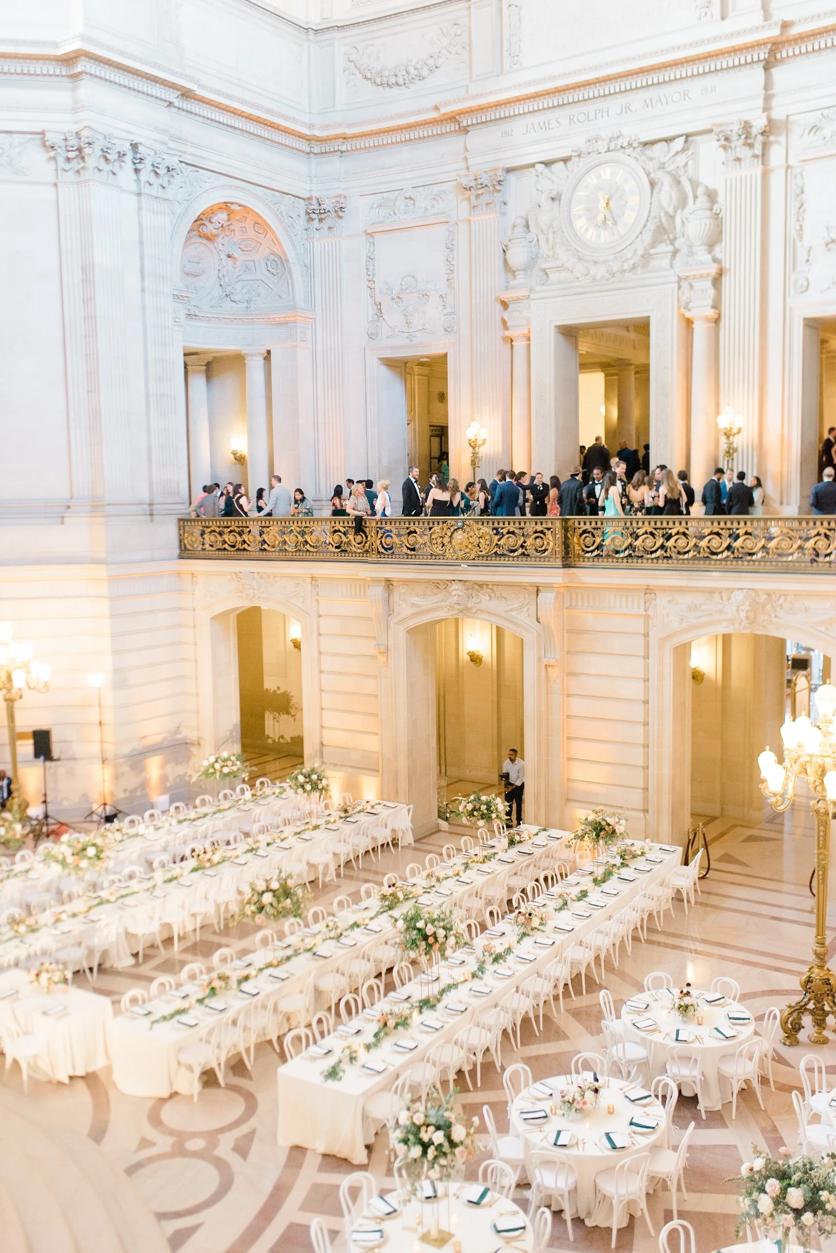 Elegant long-table wedding reception setup in the Rotunda at San Francisco City Hall with white florals and gold accents.