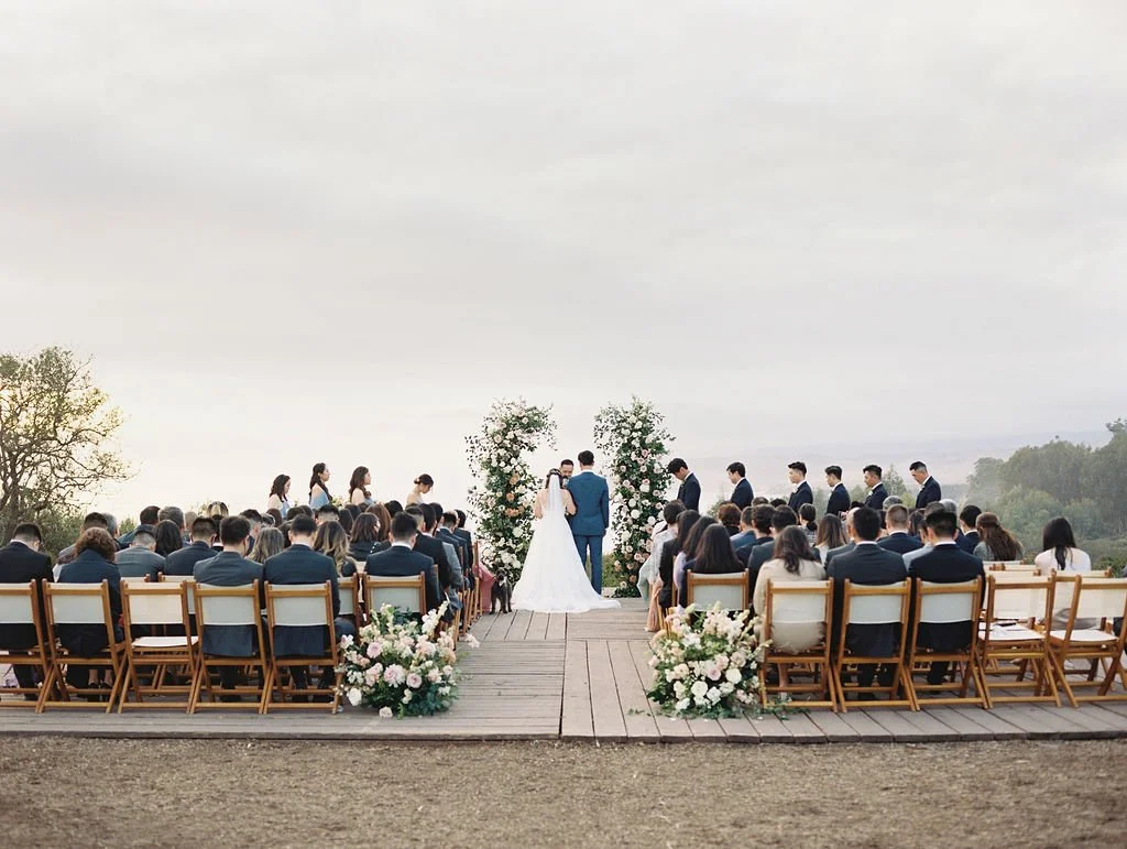 Outdoor wedding ceremony with floral aisle arrangements at Dos Pueblos Orchid Farm in Santa Barbara.