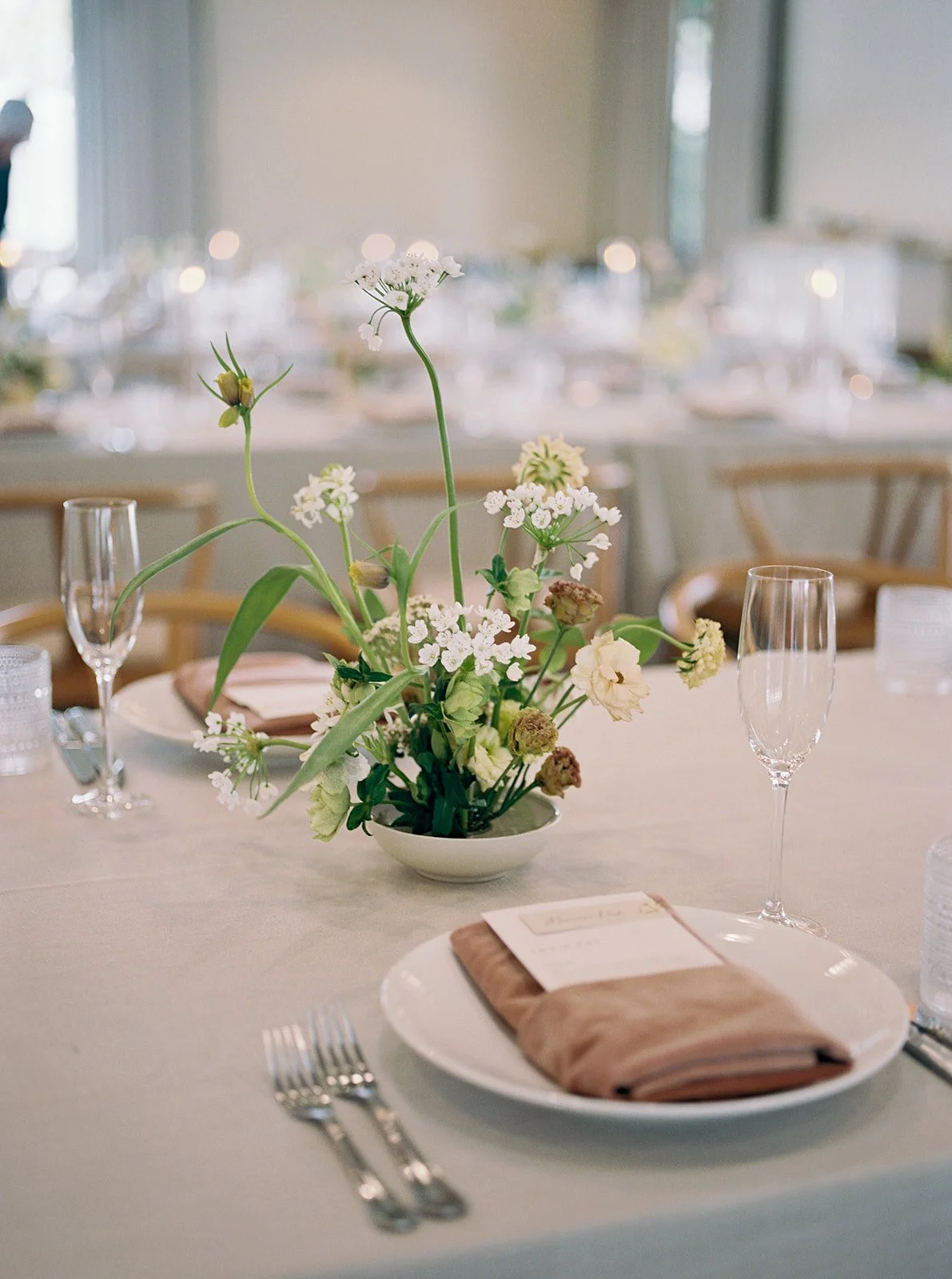 Neutral elegant wedding reception tablescape at Solage Calistoga with airy garden-style floral centerpiece and champagne flutes.