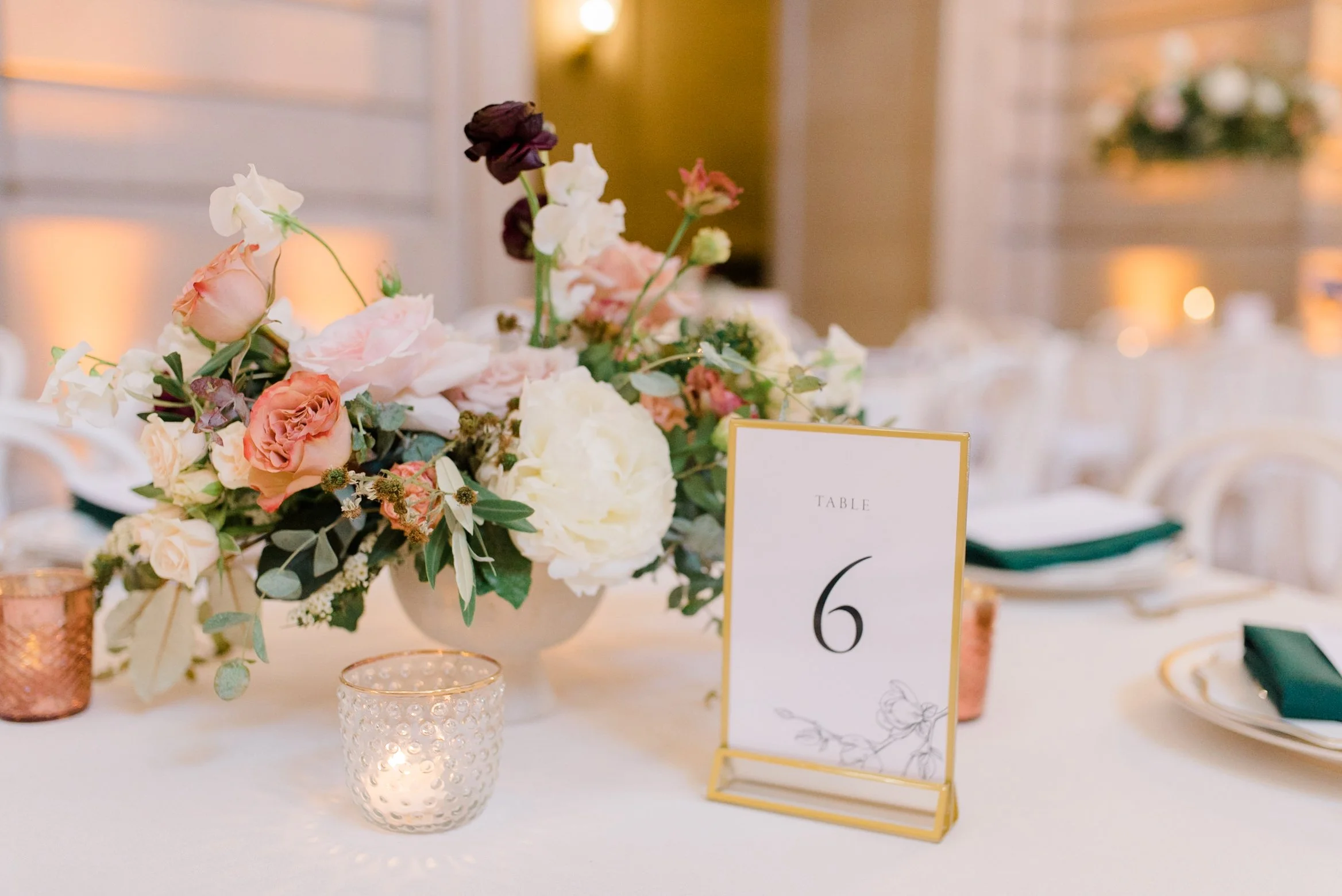 Close-up of a romantic blush and peach floral centerpiece with candles and table number at a San Francisco City Hall wedding.