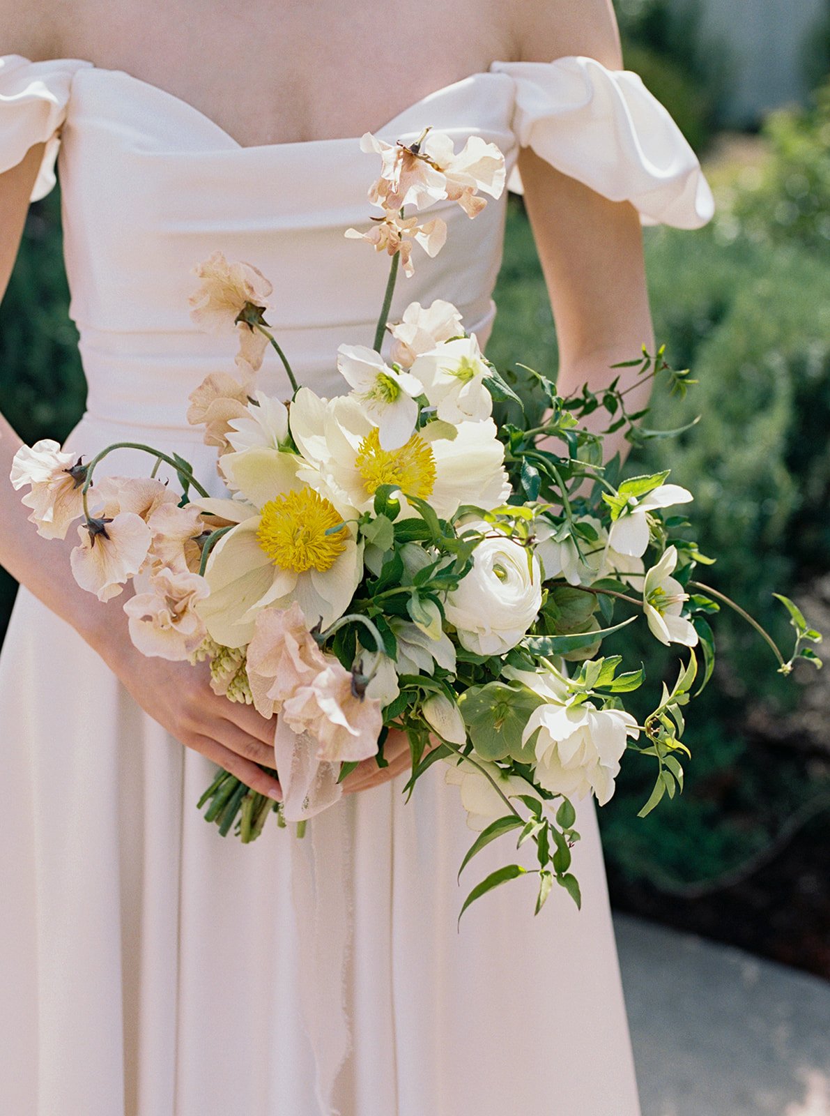 Bride holding a white and blush garden-style bouquet with delicate spring florals at Solage Calistoga.
