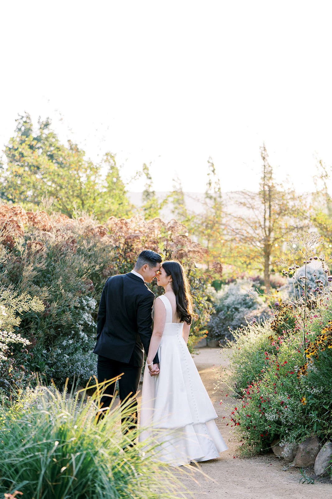 Bride and groom holding hands on a garden path at their Cornerstone Gardens wedding.