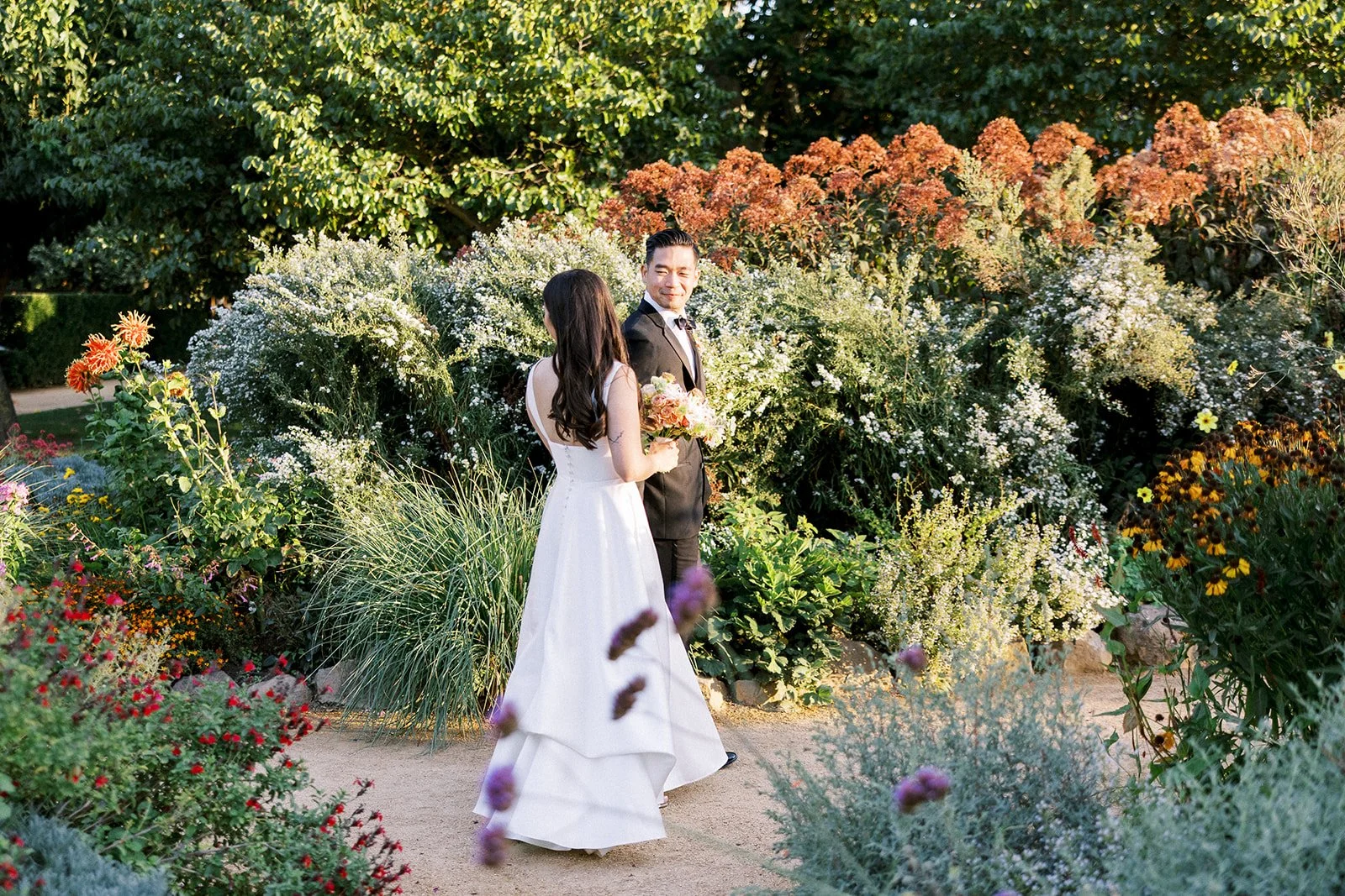 Bride and groom walking together through the gardens at Cornerstone Gardens during golden hour.