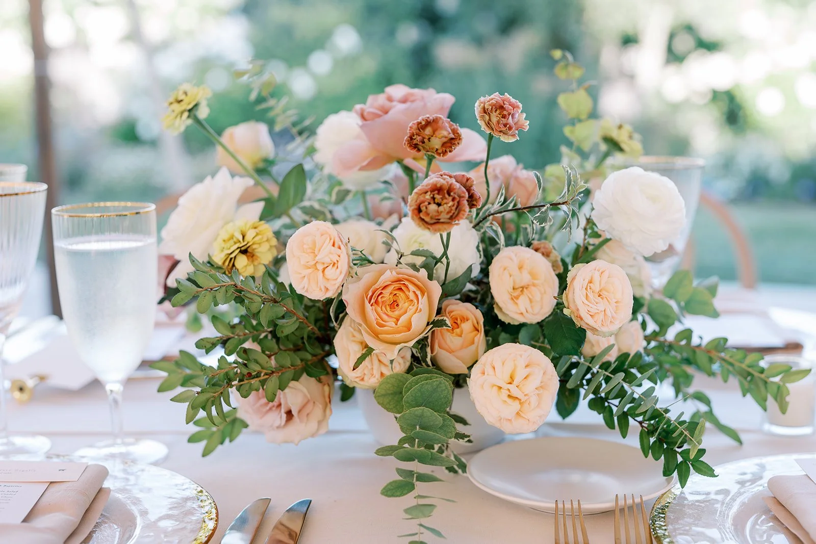 Low floral centerpiece in soft blush and peach tones designed for a Cornerstone Gardens wedding reception.