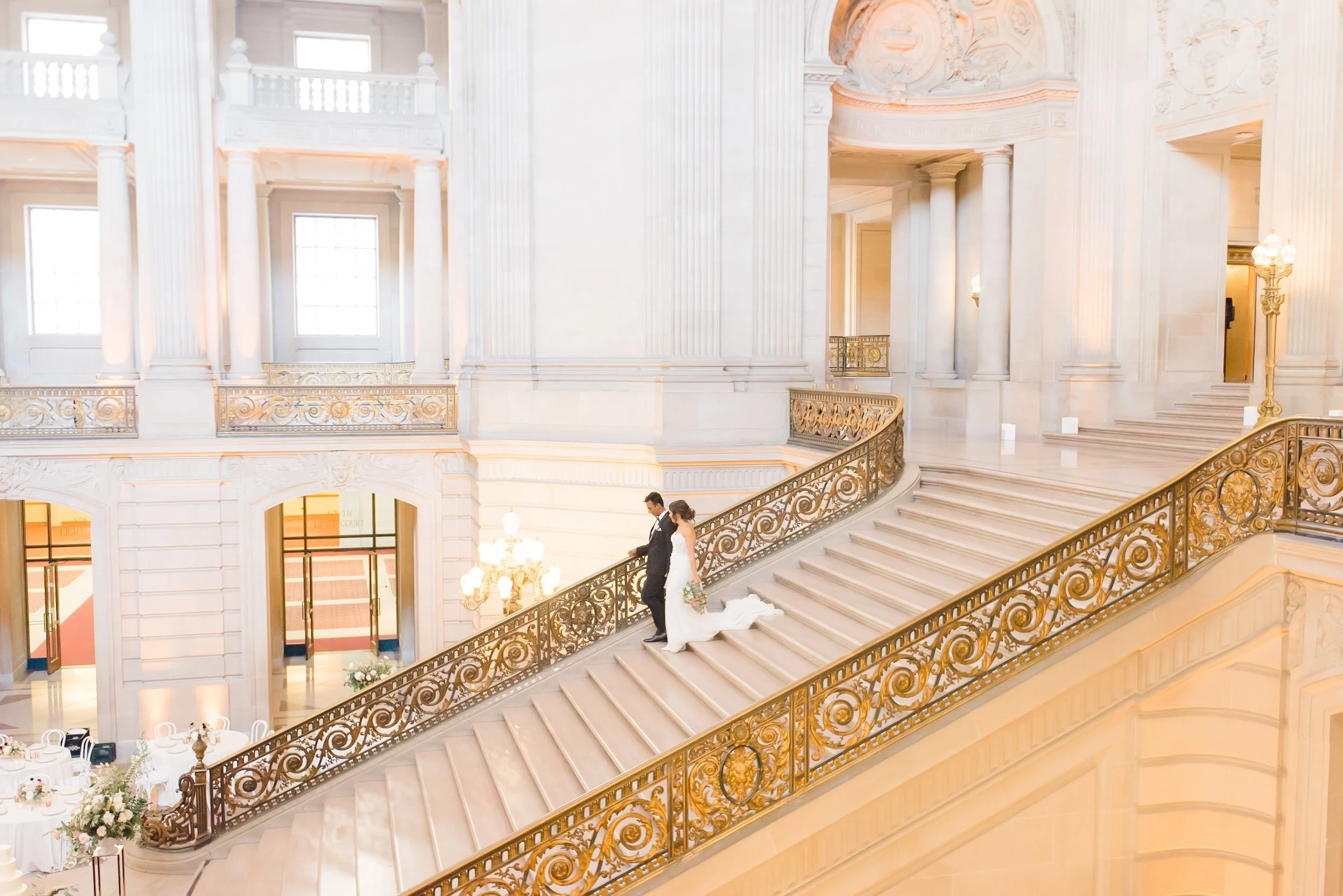 Bride and groom walking down the iconic grand staircase at San Francisco City Hall.