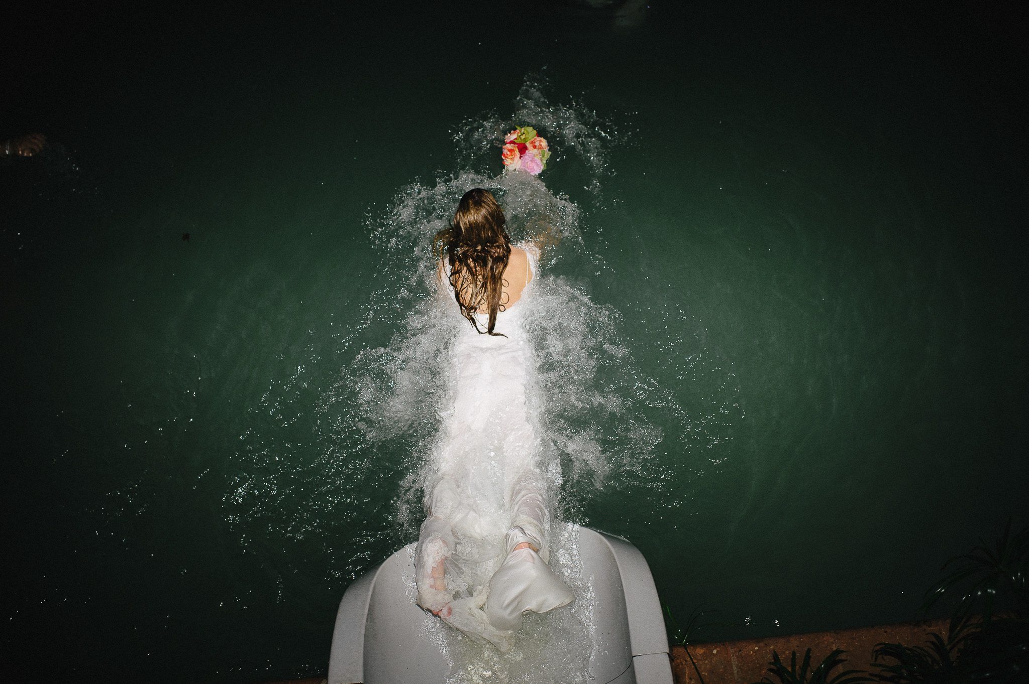 bride goes down a waterslide after wedding