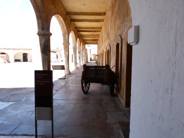 An arched shaded walkway on the main plaza. There are three levels to the Castillo.