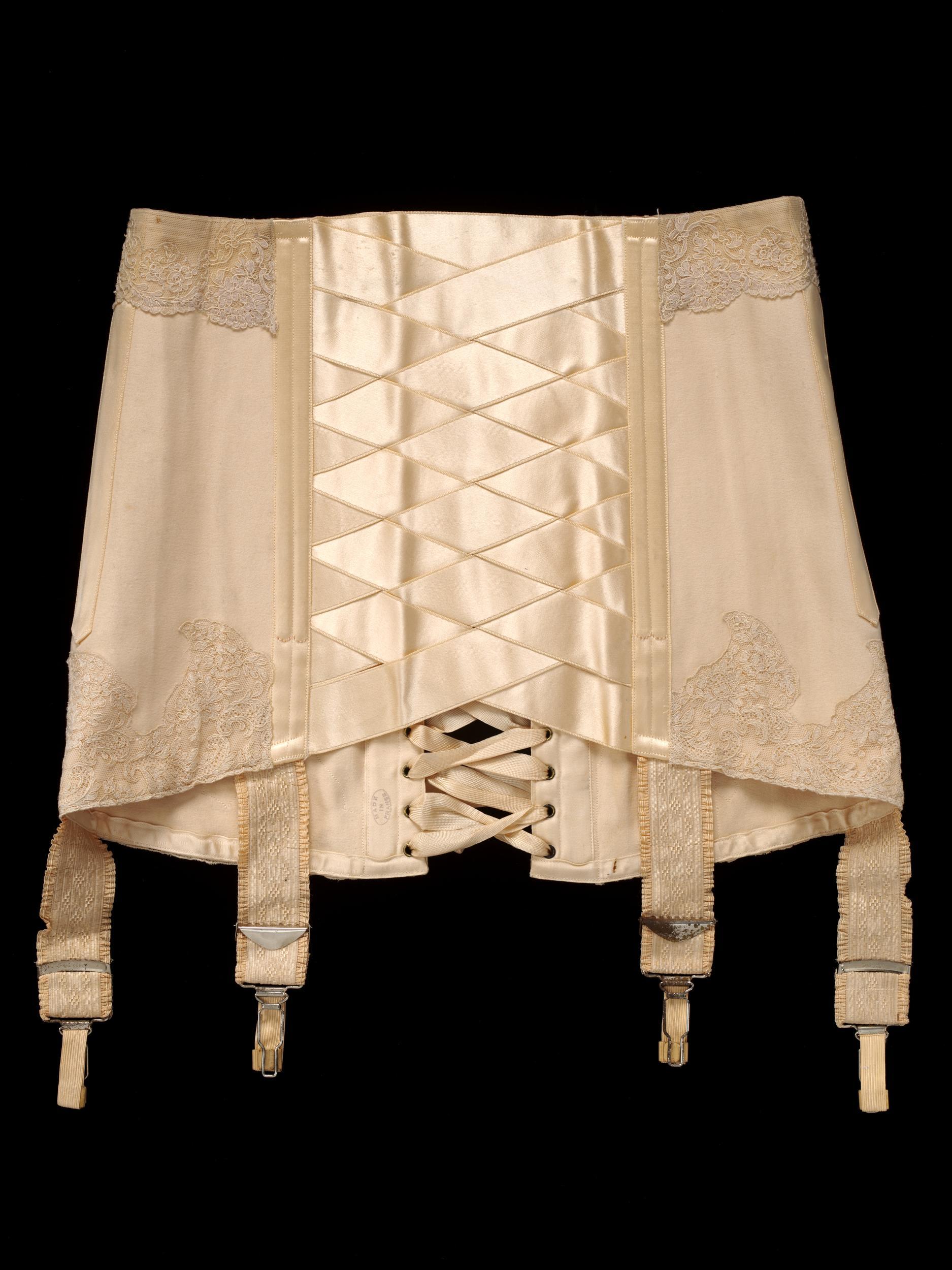 TANGO CORSET - Cotton, Silk satin ribbon, Machine lace, Metal circumference / ca. 1914 France, for Debenham & Freebody , London (V&A:T.64-1966) * Size - waist: 67cm / hip: 88cm / Length front: 25cm / back: 33cm Worn and given by Heather Firbank