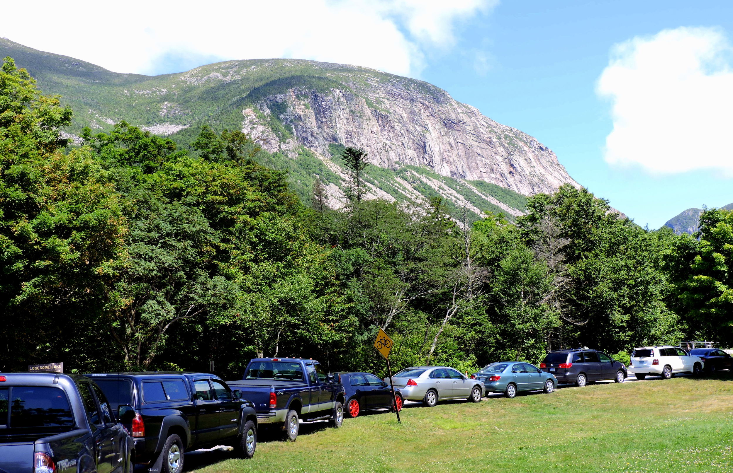 Cars parked along the entryway of the parking area for Lonesome Lake demonstrate the popularity of the area.