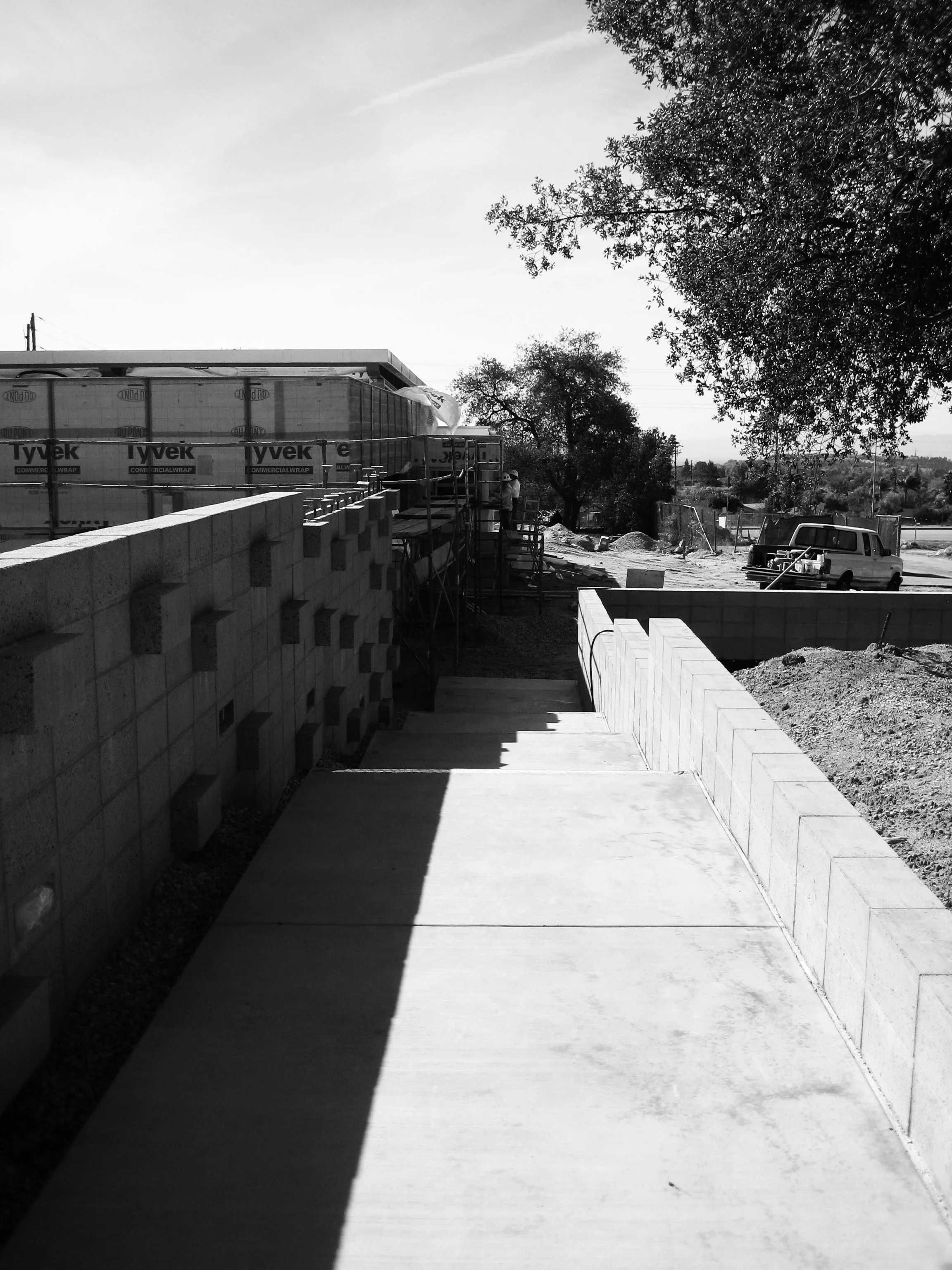 An articulated concrete block wall greets visitors approaching from the parking area. Landscaping and lighting have also since been installed in the planter to the right.