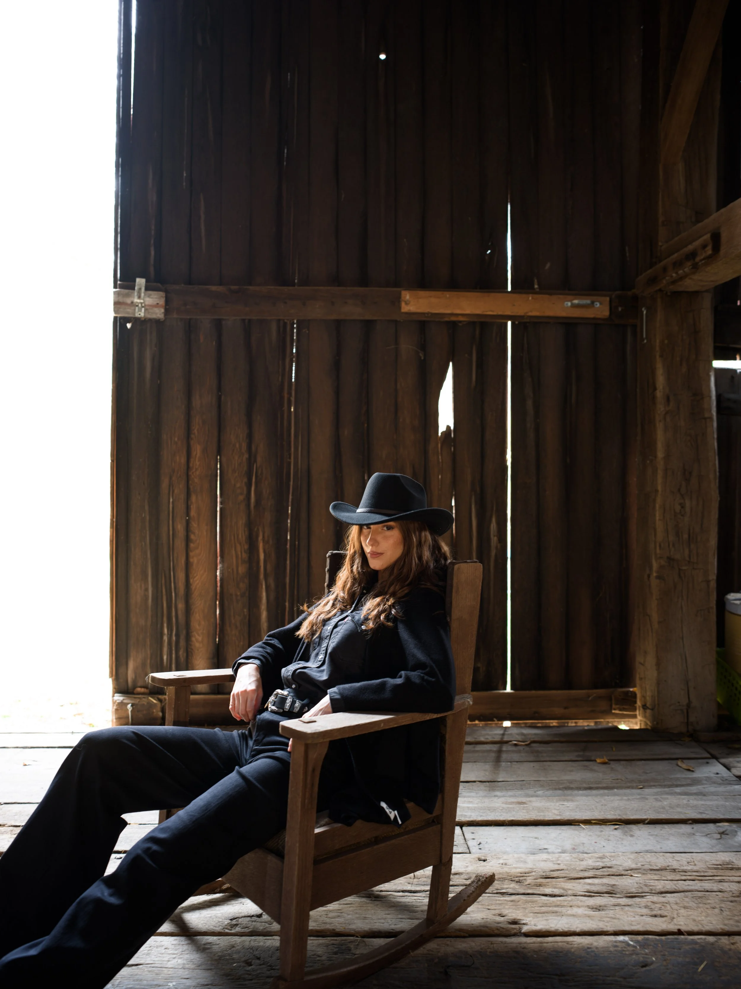 Cowgirl seated in a barn doorway