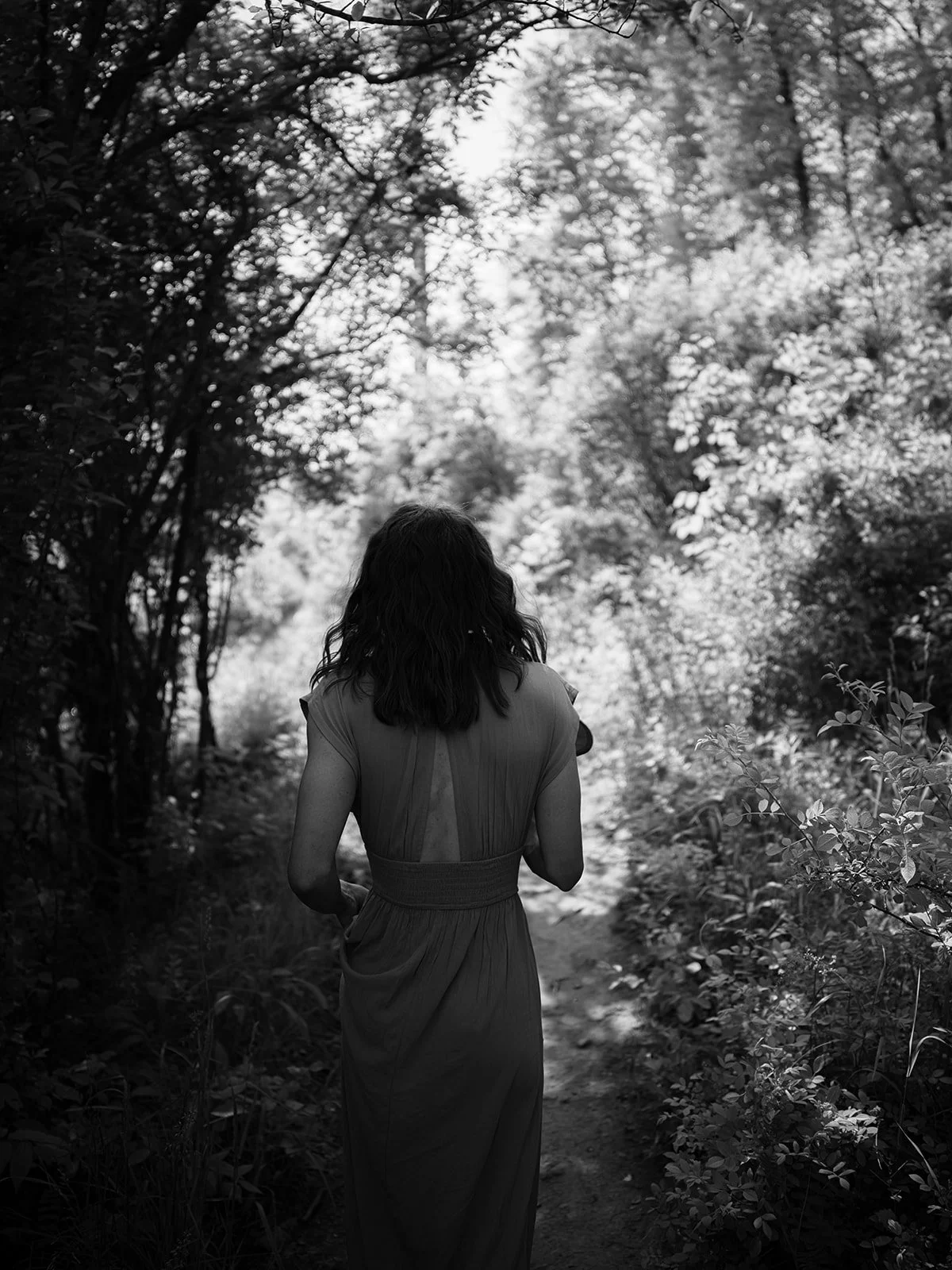 Black and white photograph walking down a wooded path