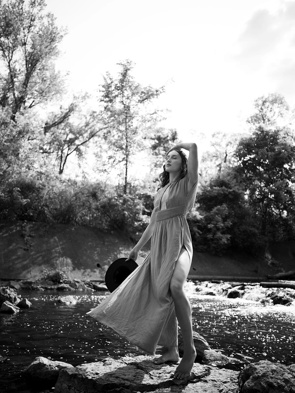 Black and white full-length portrait with a hat at the river