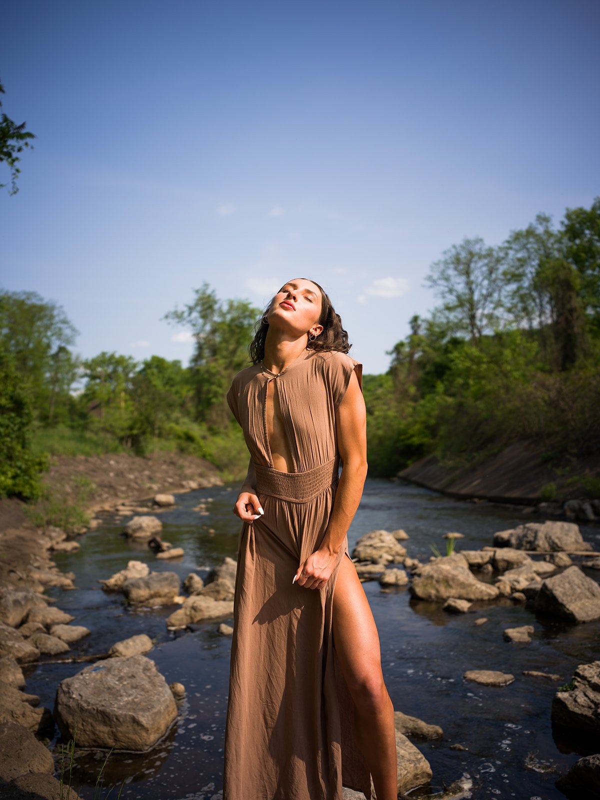 Portrait standing in a river beneath a blue summer sky