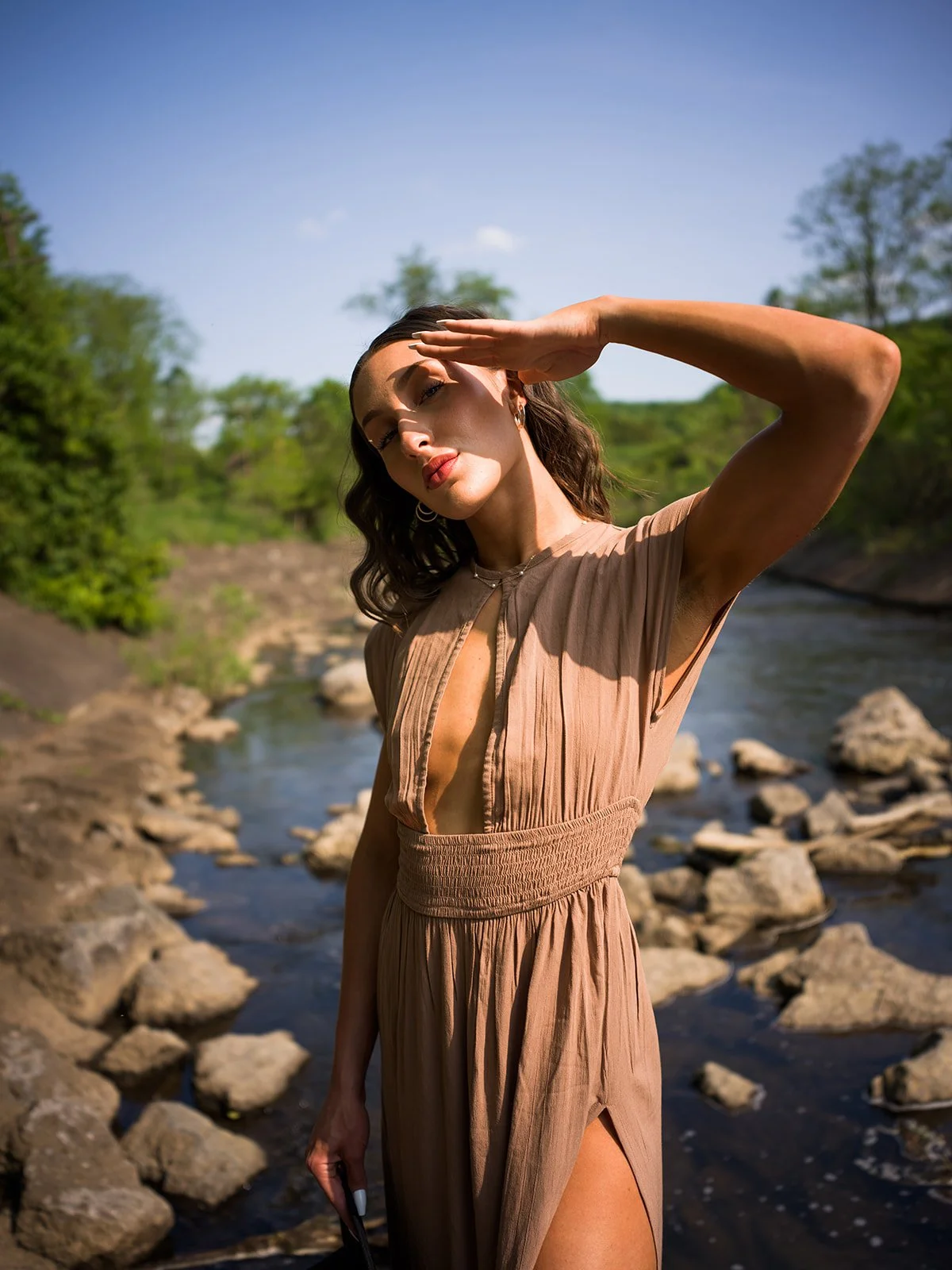 Sunlit portrait shading her eyes beside the river