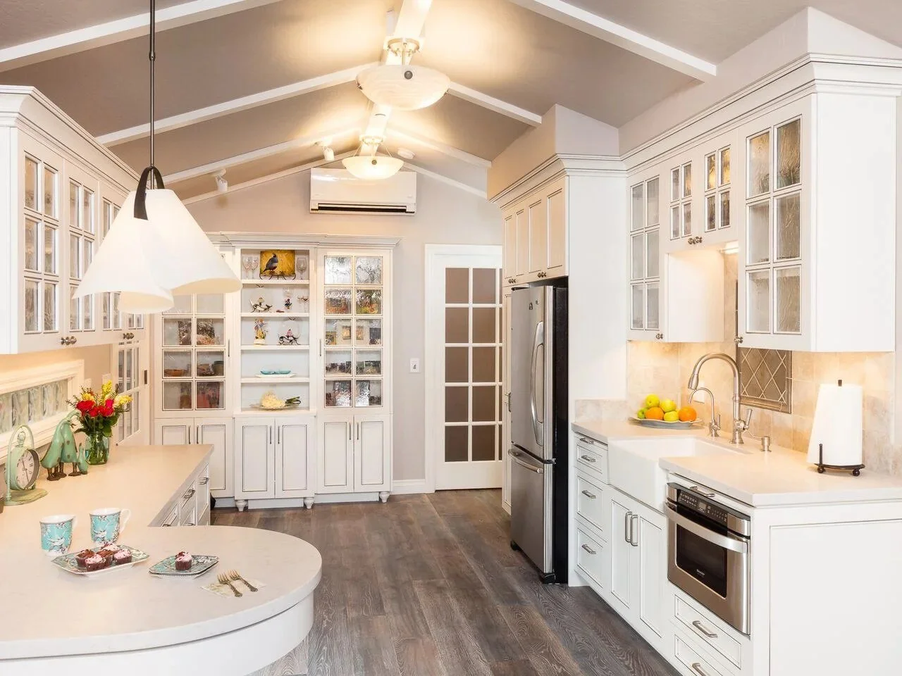 White kitchen with glass-front upper cabinets, a built-in glass-door hutch, and a vaulted ceiling