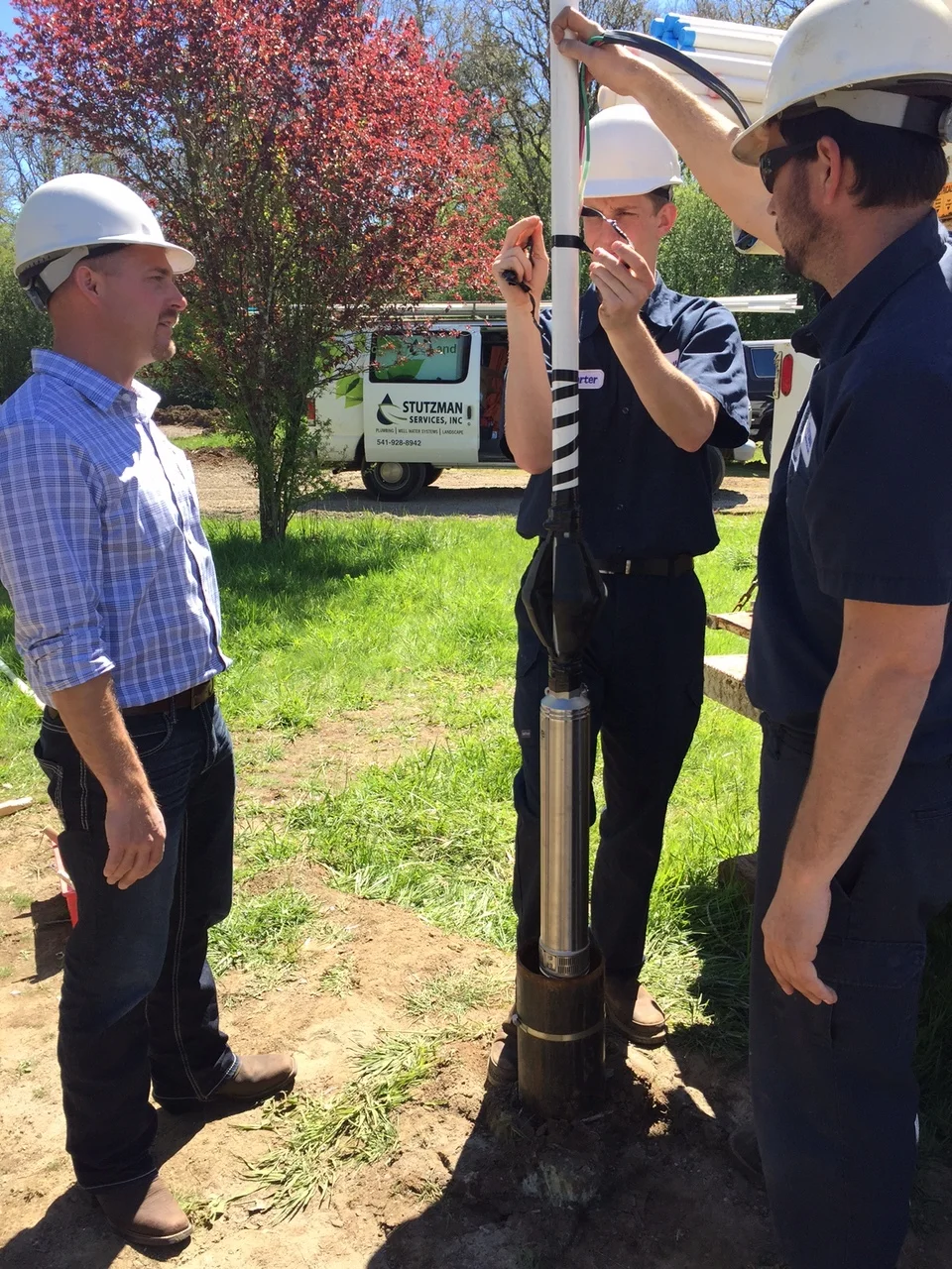 Stutzman Services Water Systems Technicians setting a submersible pump in a well.