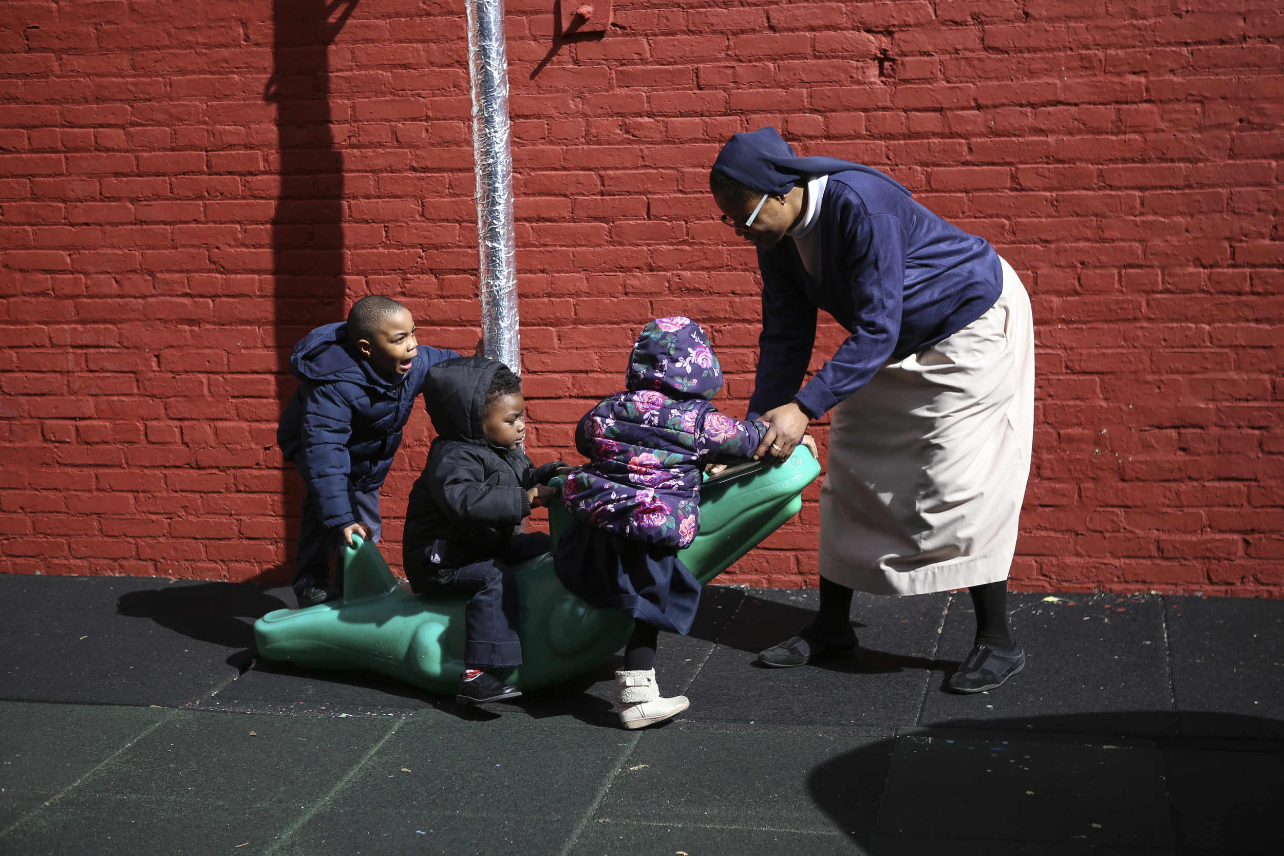  Sister Mary plays with children at St. Benedict’s Day Nursery as part of her ministry; the sisters first opened the school in 1923 as a way to help working mothers care for their children.    