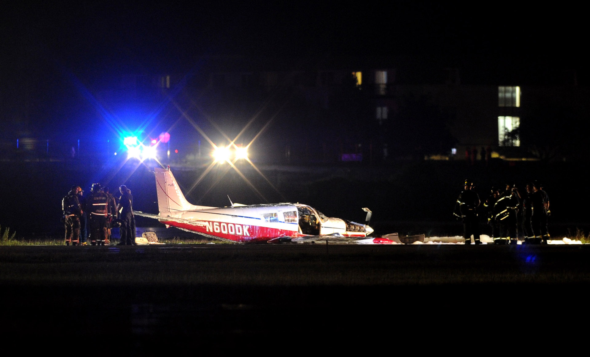  Firefighters stand around a Piper PA-32 airplane which crashed at Sikorsky Airport on Saturday, June 25, 2011. 