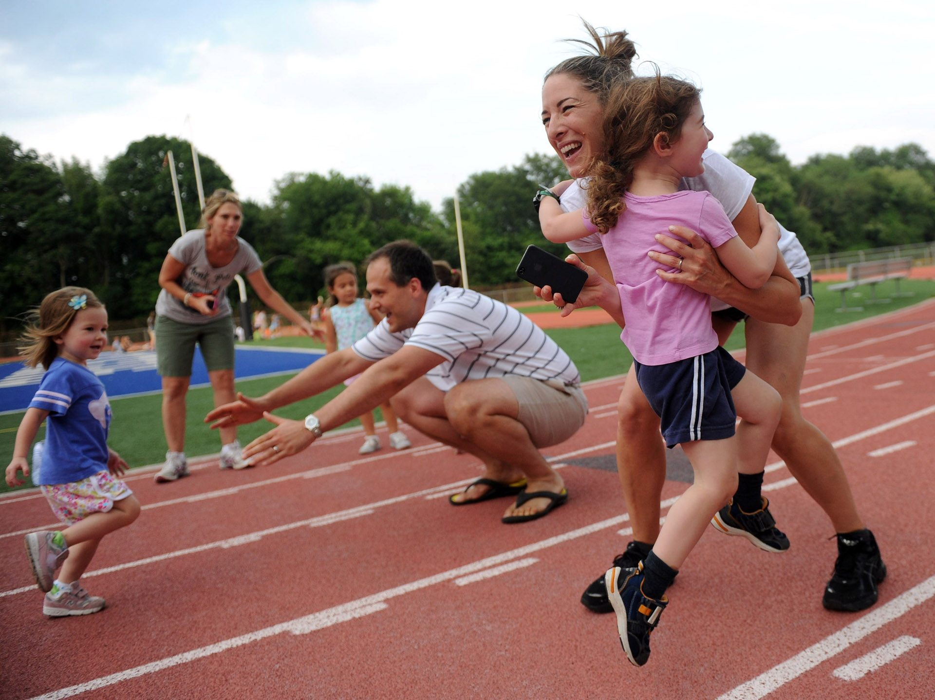 Stephanie Katz picks up her daughter, Nina, as Rob Winslow's daughter, Abby, runs into his arms during the Westport Age Group Track Meet on July 7, 2011.