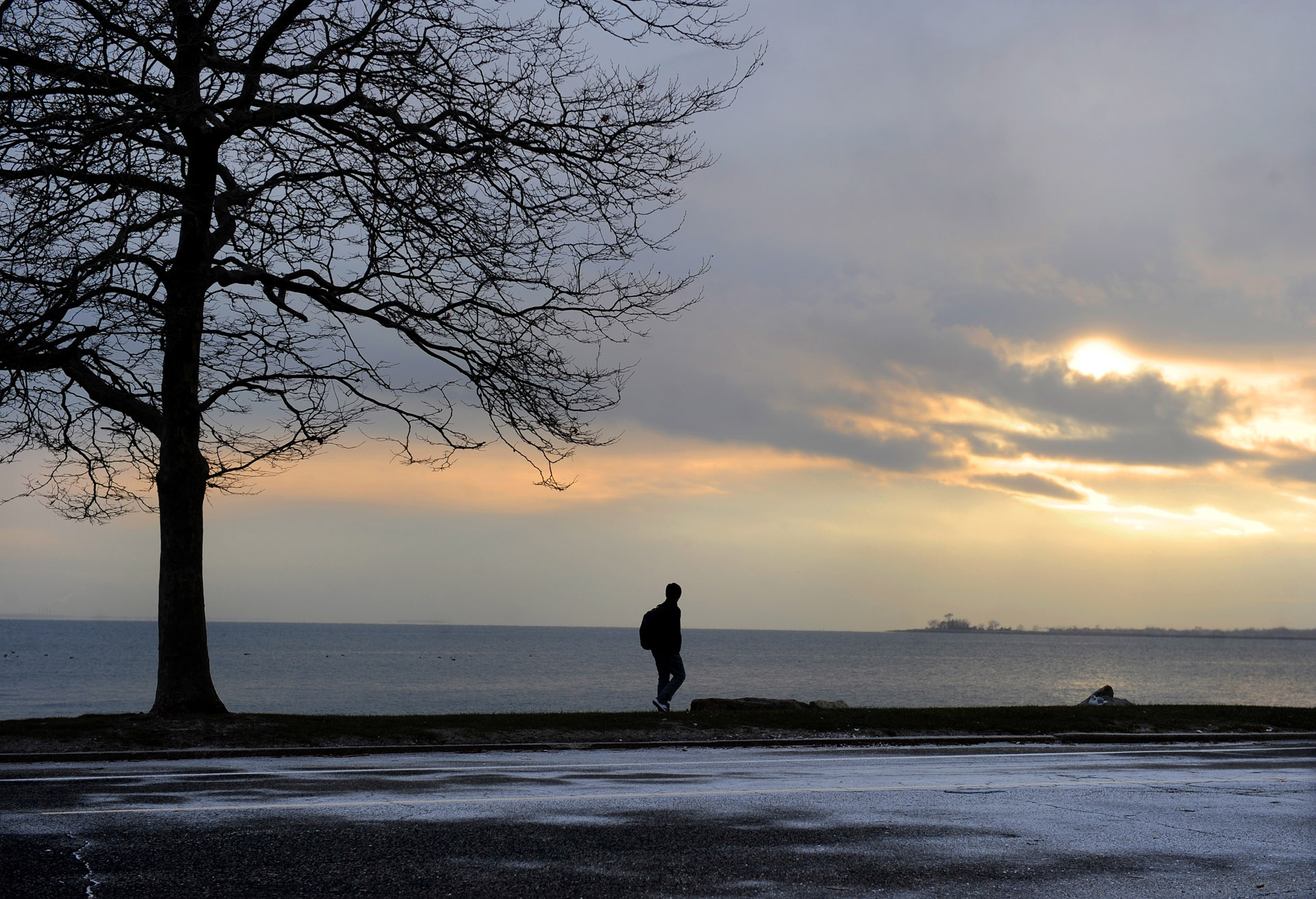  A pedestrian walks along Soundview Drive in Bridgeport on Friday as a light dusting of snow began to cover the street and the sun set on December 10, 2010. 