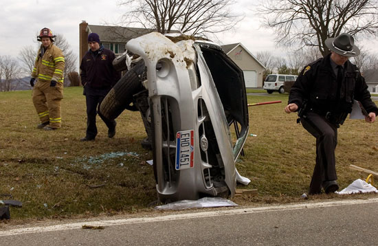  Trooper David Johnson, right, walks around a Hyundai that flipped Thursday on Egypt Pike. The driver of the car was partially ejected during the crash. 