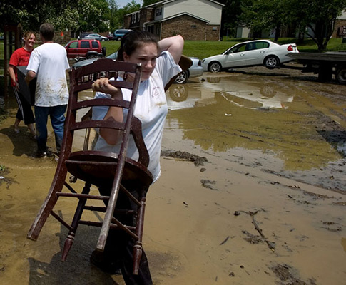  Woodland Heights residents move belongings from their flooded homes into a dumpster as submerged cars are towed after muddy flash flood water receded Wednesday morning. 