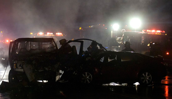  Firefighters work at the scene where a crash resulted in a fire fully engulfing a van, left, which was transporting a Chillicothe Correctional Institution inmate who died at the scene. 