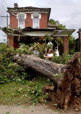  Residents and neighbors on South Hickory Street help remove branches and leaves from the tree that fell on their house during strong winds Sunday. 