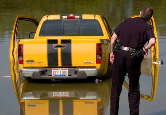  A Chillicothe police officer looks at a GMC Canyon truck that rolled into the Scioto River from a ramp in the Yoctangee Park Annex. 