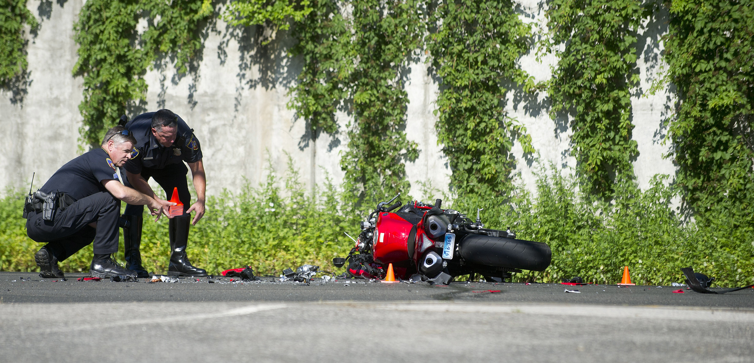  Stamford police officers work at the scene where a motorcycle and Ford Explorer collided in Stamford, Conn., on Friday, June 27, 2014. 