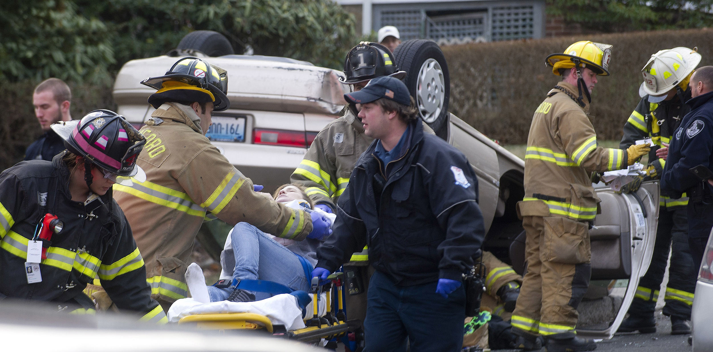  A woman is taken to an ambulance on a stretcher as her overturned Toyota sits on the sidewalk behind her after an accident on Colonial Road on Wednesday, January 1, 2014. 