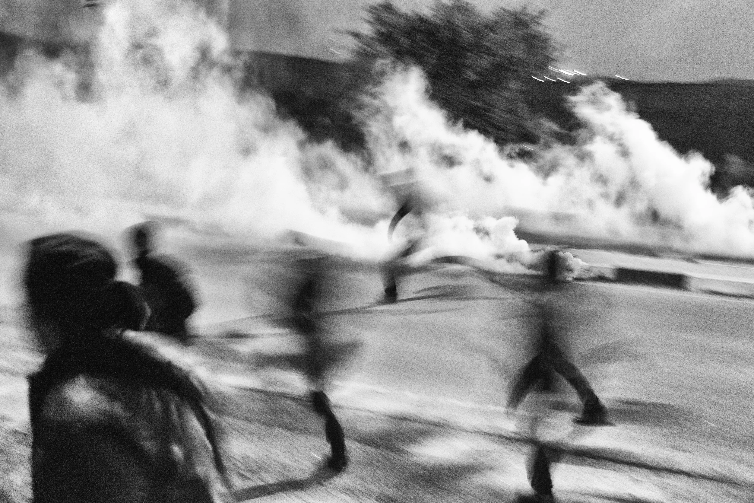 Protesters retreat as teargas grenades explode around them 