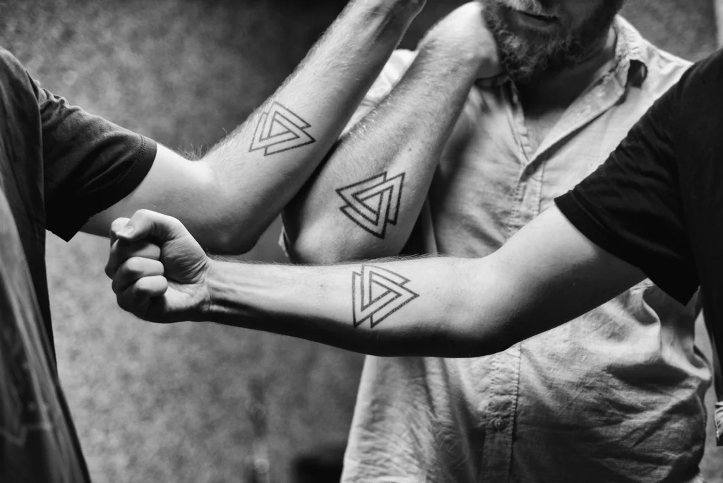 Brothers Pat, Tom and Dan Murphy of Penrose show off their matching tattoos, the symbol of the band