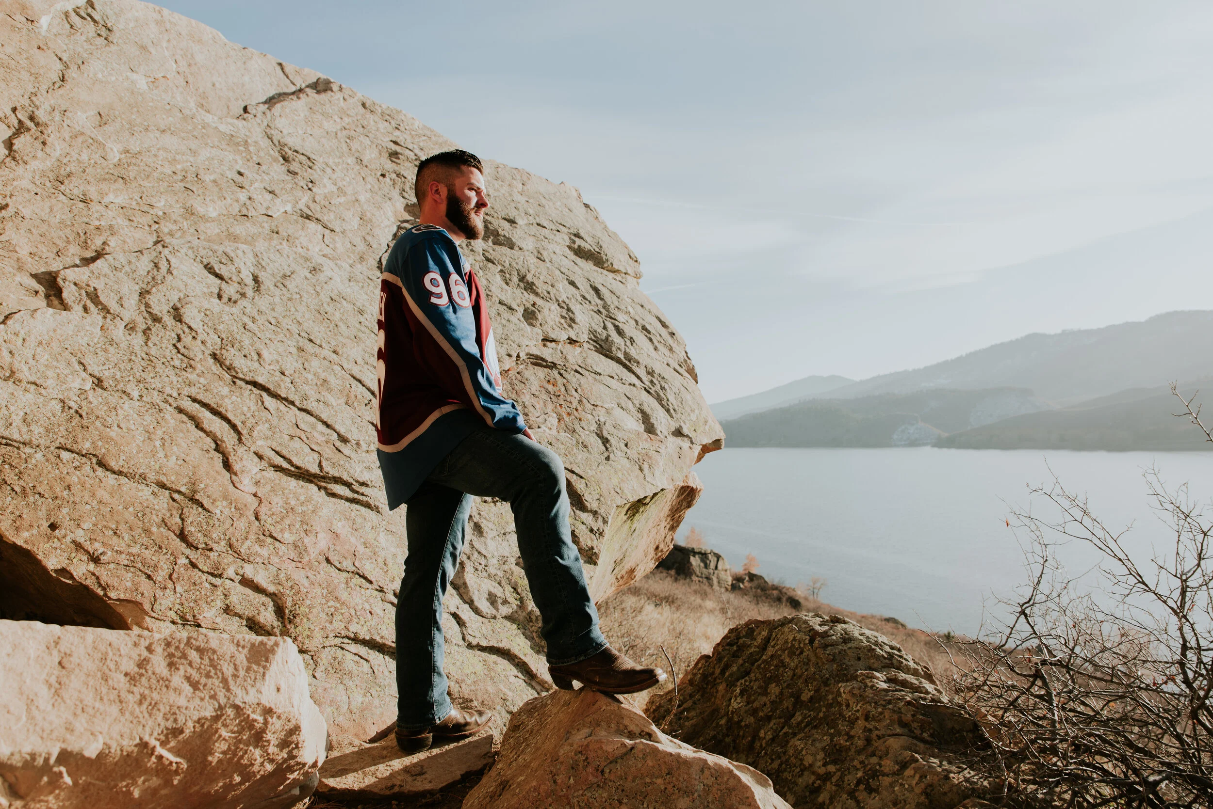 man-looks-at-lake-during-engagement-shoot