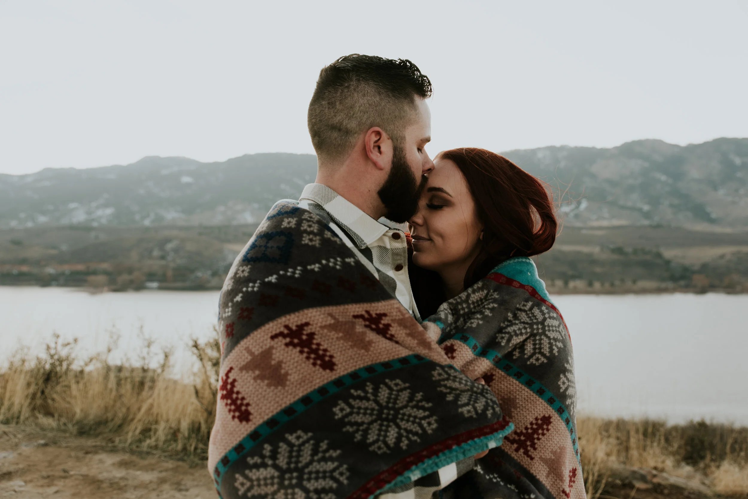 couple-embraces-in-blanket-during-engagement-session