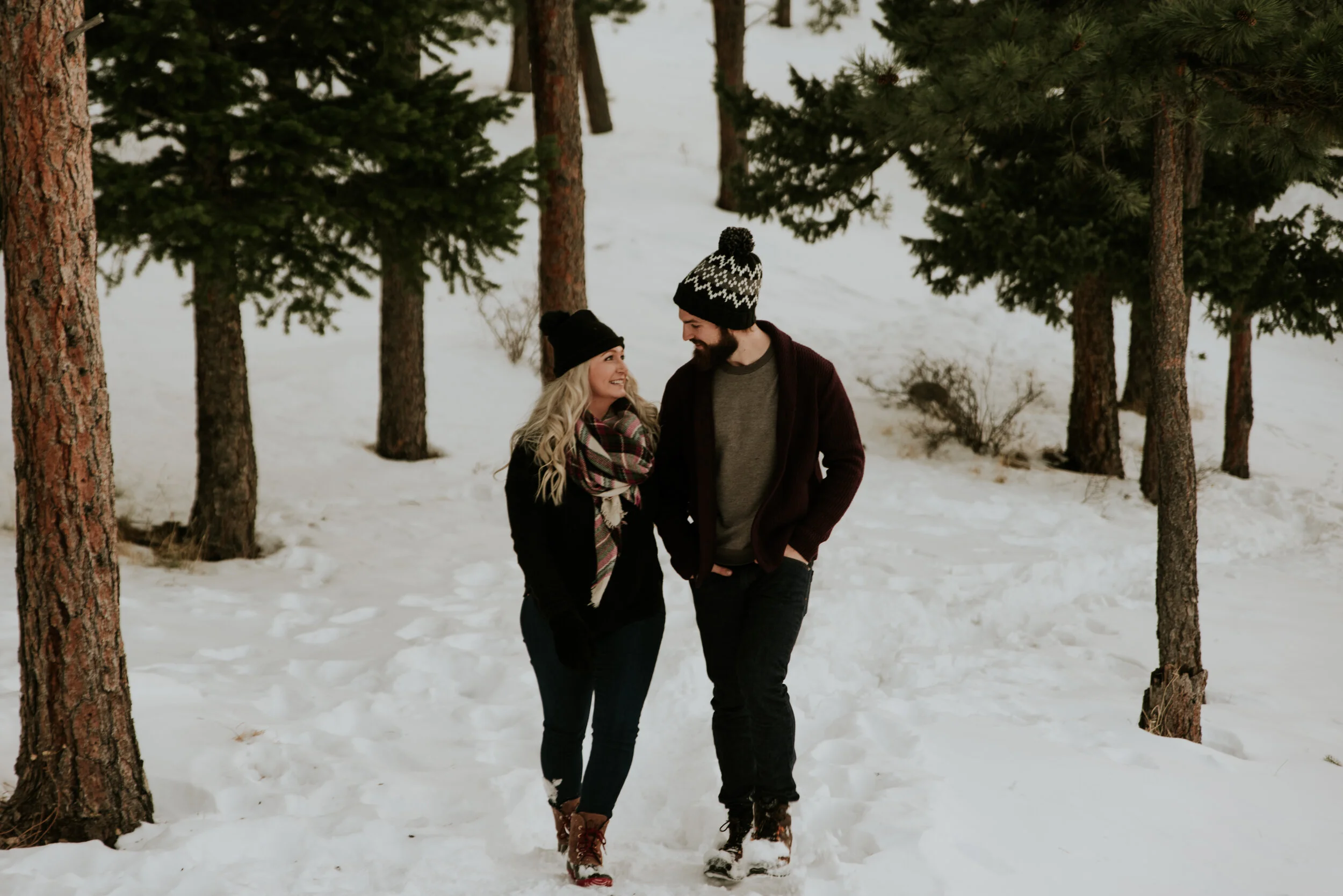 couple-walks-through-trees-in-colorado-mountains