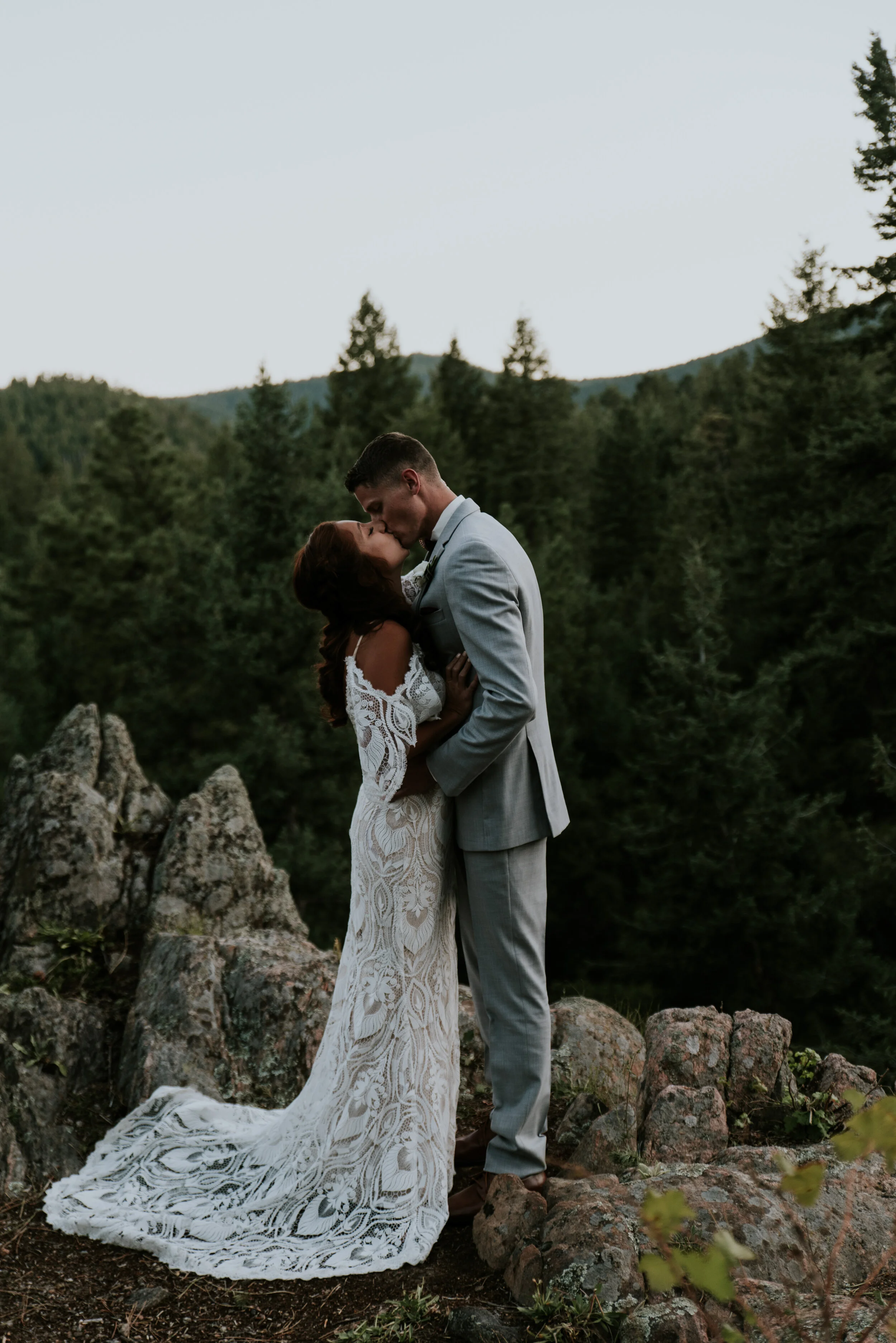 A bride and groom kiss on a mountain during the perfect elopement timeline