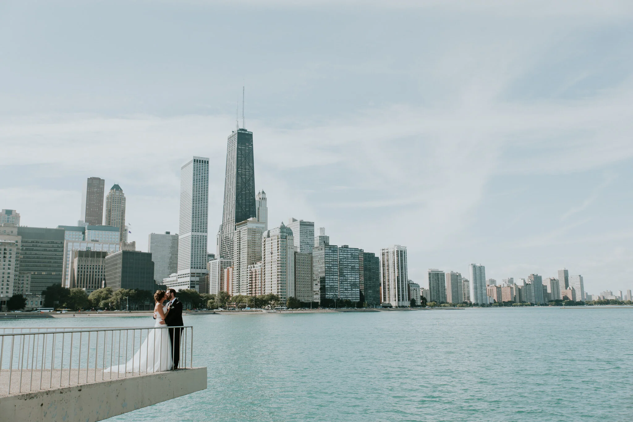 A couple kisses in front of the Chicago skyline after picking out the best elopement photography timeline