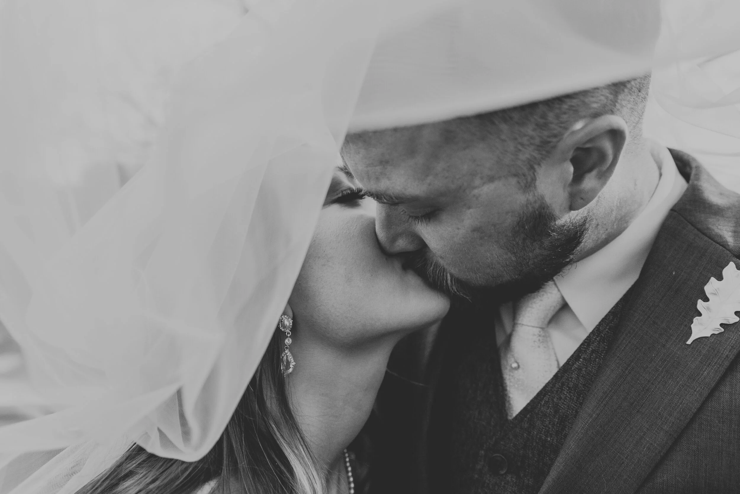 A couple kisses under a bridal veil during a destination wedding after picking out the perfect hours for an elopement timeline