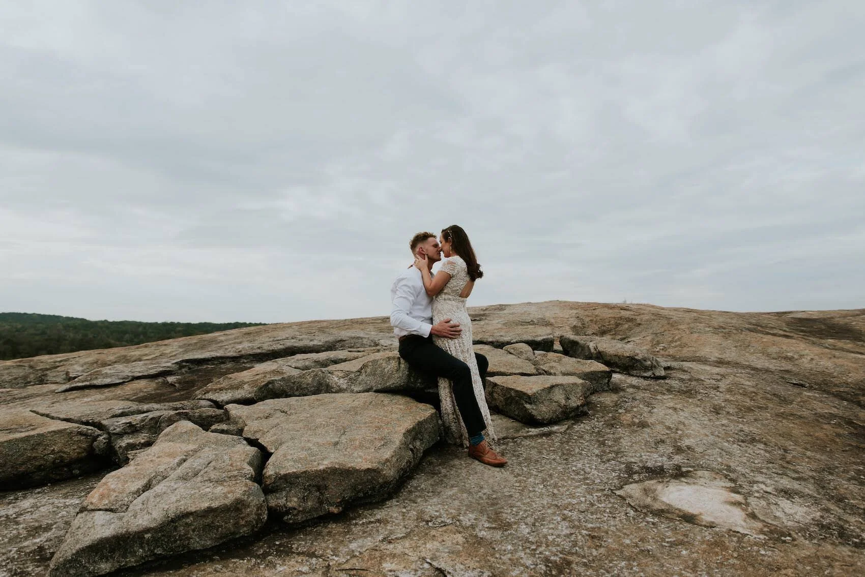 A bride and groom kiss on a mountain during an elopement after contemplating the top reasons for eloping