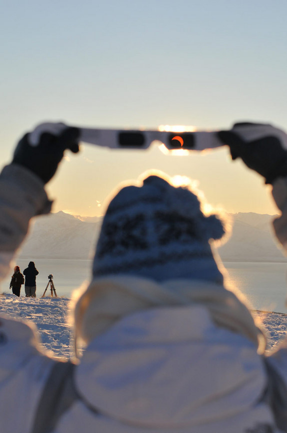 My friend holding her eclipse shades to see the setting sun about halfway eclipsed during the 2010 TSE in El Calafate, Patagonia, Argentina