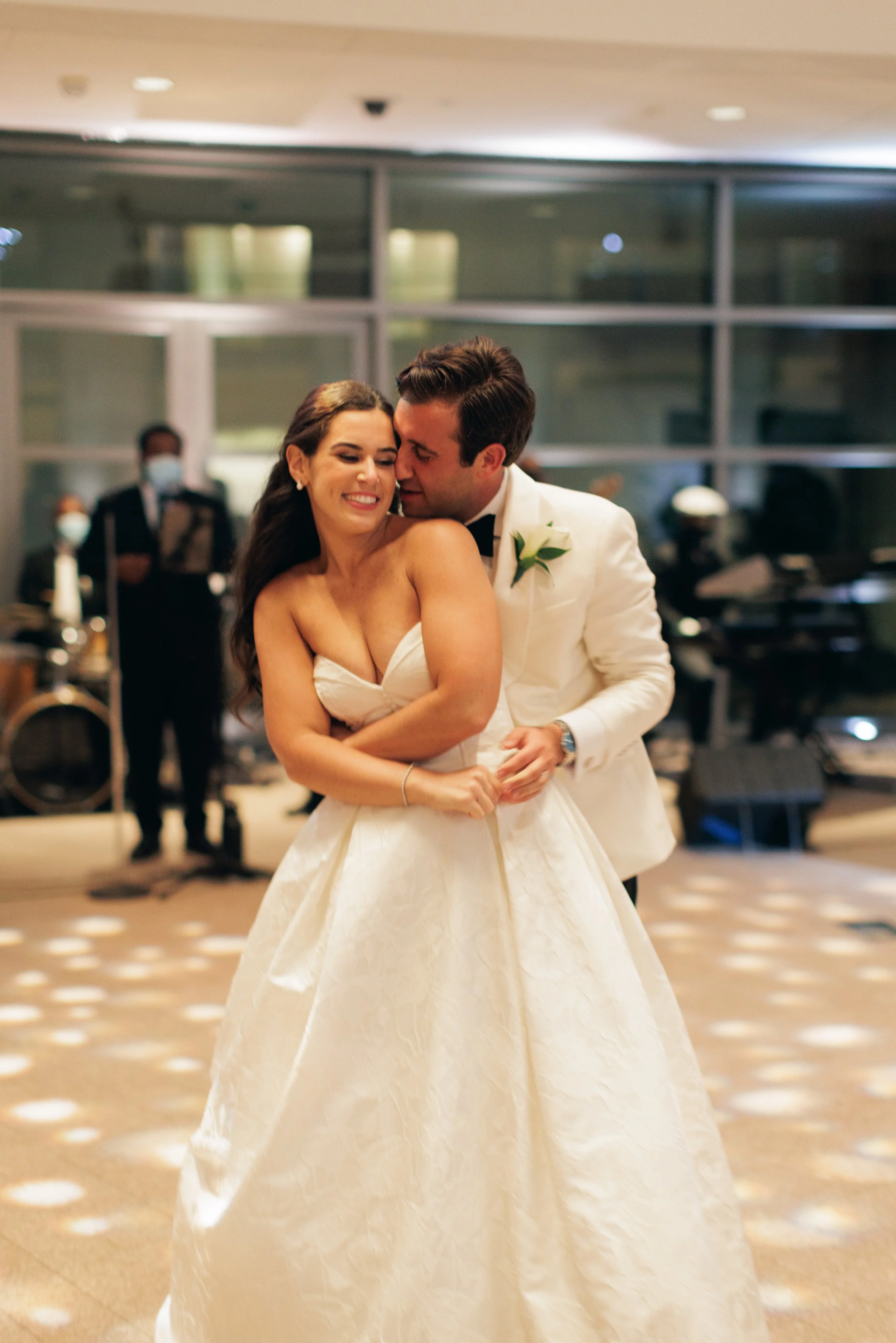 A bride and groom dancing at a wedding reception indoors.