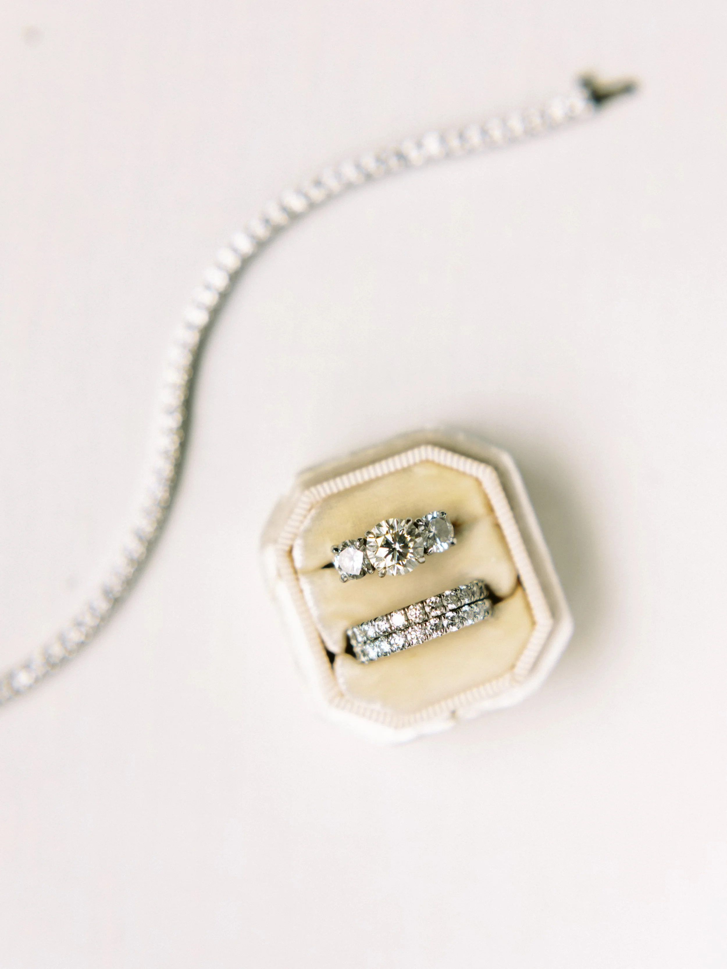 A set of diamond rings in a jewelry box, with a diamond necklace partially visible in the background.